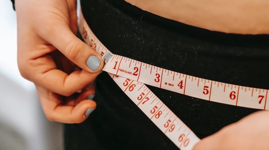 plus size woman measuring hips in gym